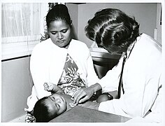 The medical inspection team at Auckland examines baby Tithe while her mother Mrs. Tulafono holds her, 1966.jpg