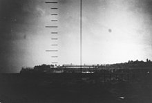 Photo en noir et blanc montrant des bâtiments peu élevés au bord de la mer.