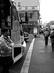 A woman standing outside a bus with its door open in winter