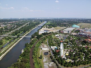 Blick vom Gasometer in Oberhausen. Die breite Wasserfläche links im Bild ist der Rhein-Herne-Kanal, weiter links (schmaler) ist die Emscher und ganz links die Autobahn 42 (Emscherschnellweg). Rechts im Bild zu sehen sind Teile des Einkaufszentrums CentrO mit Park.