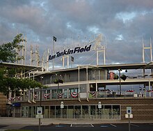 Ron Tonkin Field has a main grandstand built of concrete with a metal roof suspended by cable attached to several towers. Backside of grandstand with park signage shown.