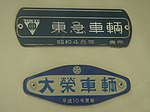 車内銘板（2代目社紋時代）（上） （京成3500形電車） この社紋は新明和に売却された立体駐車装置事業でも使用されていた。