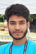 An Asian man with blue shirt with a small beard smiling