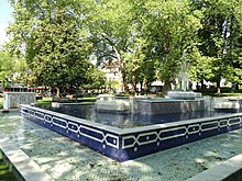 Photographie en couleurs d'une fontaine dans un espace vert public.