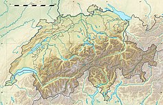 Mapa konturowa Szwajcarii, blisko dolnej krawiędzi nieco na prawo znajduje się czarny trójkącik z opisem „Monte San Giorgio”