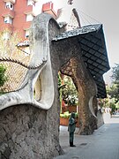 Statue de Gaudí devant grille et portail de sa création.