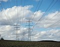 Rechts: Tonnenmast 380 kV. Links eine Hybridleitung: Unten eine 110-kV-Leitung in Donau-Anordnung, auf der obersten Traverse liegt eine Bahnstromleitung.