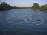 A ميلddle-sized river flows placidly between banks covered in vegetation.