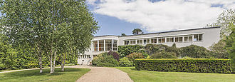 white, modernist wide two-story house in extensive gardens