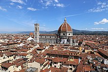 A city with red roofs and a larger domed building in the center.