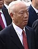 a man with white hair, wearing a suit and tie