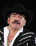 Fotografía de Joan Sebastian tocando en vivo en el Pepsi Center, vistiendo un traje tradicional mexicano negro.