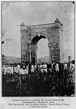 Korean spectators viewing the Korean flag on the Independence Memorial Arch. The flag which was invisible before March first of 1919 is now very clear.(조선인 관중들이 독립문 위의 태극기를 바라보고 있다. 1919년의 3·1운동 전까지는 볼 수 없었던 국기가 지금은 흔히 보인다.)