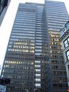 Ground-level view of a building with an all-glass, black-tinted facade; three setbacks are visible.