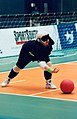 A goalballer throws the ball forward.