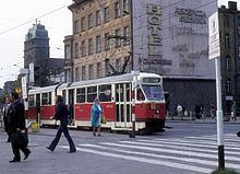 Zdjęcie. Na pierwszym planie przechodnie. Dalej dwuczłonowy tramwaj Konstal 102Na, a za nim kamienica przy pl. Brama Portowa