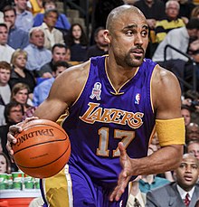 A basketball player wearing a purple jersey while dribbling the ball.