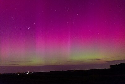 A purple and green aurora. Semi-detached houses can be seen