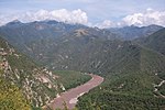 A muddy river winds along the bottom of a deep canyon.