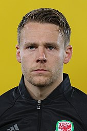 A footballer wearing a black tracksuit.