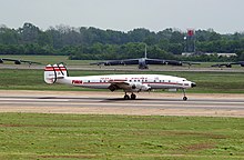 A large piston engined airliner taxiing past some large bomber aircraft