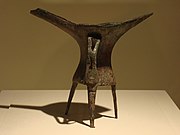 L'évolution des matières et des décors sur une même forme, le tripode jue, au cours de l'âge du Bronze ancien ; de gauche à droite : exemplaires en céramique et en bronze[87] de la période d'Erlitou sans décor, et exemplaire en bronze de la période d'Erligang décoré d'un taotie.