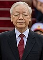 a smiling man with greying black hair, wearing a suit and tie