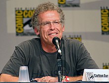 Un homme à lunette aux cheveux gris bouclés.