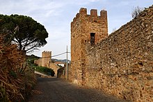 Walls and towers along a narrow, curved street