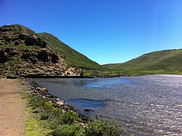 Lake and dam surrounded by green hills