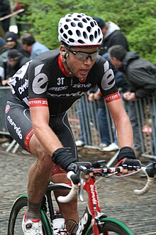 A cyclist riding in the Cervélo jersey. Spectators are visible in the background, looking behind the cyclist.