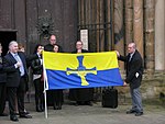 Het uitrollen van de provincievlag in de kathedraal van Durham in november 2013. James Moffat, de ontwerper van de vlag, is rechts te zien terwijl hij de vlag vasthoudt