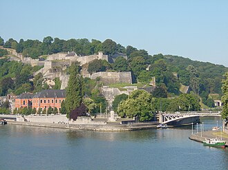 Le Parlement de Wallonie à Namur (en rose), avec, en face la Meuse, derrière la Citadelle et, à sa gauche le confluent de la Sambre et de la Meuse, l'axe des deux rivières symbolisant la partie la plus peuplée de la Wallonie