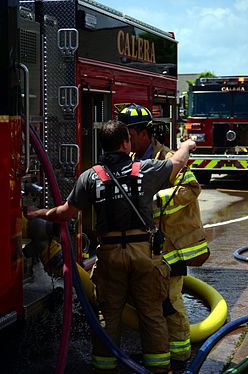 A battalion chief and firefighter confer next to a fire truck while battling a house fire in Calera, Alabama.