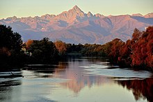 Au delà d'une belle rivière, d'une forêt, une chaîne de montagnes ; la plus majestueuse est le mont Viso.