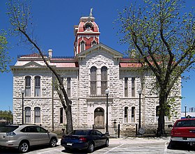 Vue d'un bâtiment de pierres blanches sur deux étages surmonté d'un clocher.