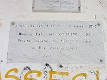 Est écrit en lettres capitales sur une plaque commémorative placée sur un mur : « A St Louis, est né le 22 septembre 1897 Mbarick Fall dit Battling Siki premier champion du monde africain de boxe professionnelle - 1897 – 1925 »