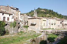 Photographie en couleur de l'ancien moulin prise depuis un pont en août 2012 le long de la rivière, le Rieutord.).