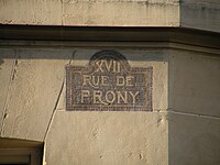 Plaque de rue (non réglementaire) de la rue de Prony, à l’angle de la rue Henri-Rochefort.