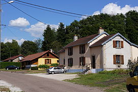 Une grande maison mitoyenne et deux autres plus petites, simples.