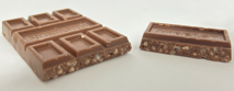 A Feastables Milk Crunch chocolate bar split in half to reveal crisp rice