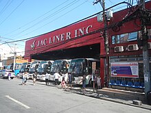 A bus terminal along the avenue, painted red