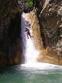 un canyoniste à mi hauteur d'un toboggan de huit mètres environ