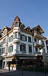 Am Marktplatz gelegenes Wohn- und Geschäftshaus mit dem Café de Paris. In Jugendstil-ähnlicher Bauweise, 1995 renoviert.