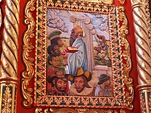 A painting on carved wood showing various people, among others: American Indians, a black person, two European-looking persons. The central figure is St. Paul, with a halo holding a book with red cover in his left and a sword in his right hand.