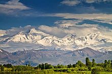 Montañas con picos entre las nubes pero con laderas cubiertas de nieve con un hermoso brillo.