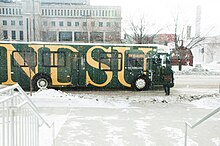 A MATBUS vehicle waits in the snow while a rider boards the bus.