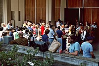 Photographie en couleur représentant une foule de badauds à l'entrée d'un bâtiment.