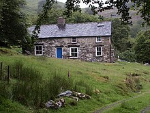 A colour photograph of a stone cottage on a hill