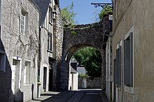 Photographie en couleurs d'une portion de muraille percée d'une porte.